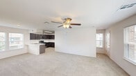 Located in Broken Arrow, Oklahoma, this three-story townhome offers a well-organized layout distributed across three distinct levels. The ground floor features an attached garage with a automatic opener, concrete flooring, and interior access — providing both secure parking and additional storage potential. The main living level showcases an open-concept kitchen and living room bathed in natural light from multiple windows. The kitchen is equipped with dark espresso cabinetry, marble-style quartz countertops, a tile backsplash, stainless steel appliances including a dishwasher, range, and microwave, and a peninsula that doubles as a prep and serving area. The living area features plush carpet and a ceiling fan with light fixture. The upper floor is home to the generously sized primary bedroom, which is flooded with natural light through multiple windows and includes a ceiling fan, carpeted floors, and access to two walk-in closets with wire shelving systems. Three bathrooms serve the home, one of which features decorative patterned tile flooring, subway tile shower surround, and a bright window with neighborhood views. Staircases connect all three levels, completing this functional multi-story layout.
