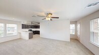 Located in Broken Arrow, Oklahoma, this three-story townhome offers a well-organized layout distributed across three distinct levels. The ground floor features an attached garage with a automatic opener, concrete flooring, and interior access — providing both secure parking and additional storage potential. The main living level showcases an open-concept kitchen and living room bathed in natural light from multiple windows. The kitchen is equipped with dark espresso cabinetry, marble-style quartz countertops, a tile backsplash, stainless steel appliances including a dishwasher, range, and microwave, and a peninsula that doubles as a prep and serving area. The living area features plush carpet and a ceiling fan with light fixture. The upper floor is home to the generously sized primary bedroom, which is flooded with natural light through multiple windows and includes a ceiling fan, carpeted floors, and access to two walk-in closets with wire shelving systems. Three bathrooms serve the home, one of which features decorative patterned tile flooring, subway tile shower surround, and a bright window with neighborhood views. Staircases connect all three levels, completing this functional multi-story layout.