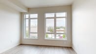 Located at 420 Center St NE in the heart of Salem, Oregon, this efficiently designed studio unit offers a well-planned single-floor layout that makes the most of its compact footprint. The main living area is bright and airy, anchored by two large, floor-to-ceiling windows that flood the space with natural light and frame views of the surrounding downtown Salem cityscape. Light-toned luxury vinyl plank flooring runs throughout, contributing to a clean, modern aesthetic complemented by neutral wall tones and crisp white trim.

The kitchen is thoughtfully appointed with dark wood cabinetry, white quartz countertops, a stainless steel sink, and a sleek tile backsplash in a soft linear pattern. Black stainless appliances — including a refrigerator, electric range, dishwasher, and over-the-range microwave — complete the contemporary look. A built-in closet with open shelving provides convenient storage adjacent to the living area, and a stacked washer and dryer unit is tucked neatly into a dedicated space within the unit.

The bathroom features a wood-tone vanity with a white countertop, an undermount sink, a mirror, and matte black fixtures and hardware, offering a polished, modern finish. Recessed lighting throughout adds a refined touch to this well-designed urban unit.