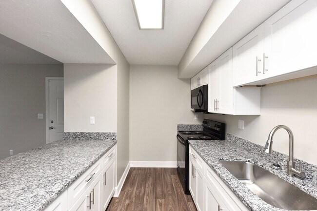 Cocina con encimeras de granito, electrodomésticos negros y gabinetes modernos. - Harpeth Trace