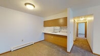 This single-floor unit offers a straightforward, functional layout designed for comfortable everyday living. The living area is generously sized, featuring neutral carpet, a textured ceiling, and a sliding glass door that brings in natural light and opens to an outdoor view of greenery. A baseboard heating unit runs along the wall, providing efficient warmth throughout. An integrated kitchen pass-through with warm wood-toned cabinetry visually connects the living space to the kitchen area.

The galley-style kitchen is well-equipped with ample white cabinetry trimmed in wood, generous counter space, a stainless steel sink, a white refrigerator, and an electric range. Light tile flooring completes the practical cooking space.

Multiple bedrooms are carpeted and feature white walls, textured ceilings, baseboard heaters, and natural light from windows with blinds. Each bedroom includes at least one built-in closet with bifold doors, providing substantial storage. One bedroom offers dual closets for added convenience.

The bathroom includes a full-size soaking tub with a clean, all-white surround. Throughout the unit, wood-toned baseboards and trim provide consistent detailing, contributing to a cohesive and understated aesthetic.