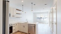 Located at 770 Water Street in Framingham, MA, this thoughtfully designed one-bedroom, one-bathroom residence offers a clean, contemporary aesthetic across a well-utilized single floor. The open-concept kitchen and living area serves as the heart of the home, featuring crisp white cabinetry with matte black hardware, a classic white subway tile backsplash, and light quartz countertops that extend into a peninsula with an undermount sink. Stainless steel appliances — including a refrigerator, range, microwave, and dishwasher — complement the modern palette, while warm wood-tone open shelving adds visual depth. Pendant lighting anchors the kitchen space, and recessed lighting carries throughout. Light hardwood flooring flows seamlessly through the living area, bedroom, and hallway, lending warmth and continuity. The living area benefits from a large window that invites natural light and outdoor views. The bedroom is a comfortable, well-proportioned retreat with its own window and direct access to a dedicated walk-in closet equipped with wire shelving. The bathroom is finished with hexagonal white floor tile, a glass-enclosed subway tile shower, and white upper cabinetry, reflecting a cohesive and refined design sensibility throughout the unit.