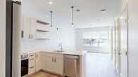 Located at 770 Water Street in Framingham, MA, this thoughtfully designed one-bedroom, one-bathroom residence offers a clean, contemporary aesthetic across a well-utilized single floor. The open-concept kitchen and living area serves as the heart of the home, featuring crisp white cabinetry with matte black hardware, a classic white subway tile backsplash, and light quartz countertops that extend into a peninsula with an undermount sink. Stainless steel appliances — including a refrigerator, range, microwave, and dishwasher — complement the modern palette, while warm wood-tone open shelving adds visual depth. Pendant lighting anchors the kitchen space, and recessed lighting carries throughout. Light hardwood flooring flows seamlessly through the living area, bedroom, and hallway, lending warmth and continuity. The living area benefits from a large window that invites natural light and outdoor views. The bedroom is a comfortable, well-proportioned retreat with its own window and direct access to a dedicated walk-in closet equipped with wire shelving. The bathroom is finished with hexagonal white floor tile, a glass-enclosed subway tile shower, and white upper cabinetry, reflecting a cohesive and refined design sensibility throughout the unit.