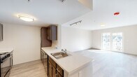 This thoughtfully designed one-bedroom, one-bathroom residence offers an efficient and functional single-floor layout. The open-concept living and kitchen area serves as the heart of the space, where a peninsula with light countertops and a stainless steel sink seamlessly connects the kitchen to the living area. The kitchen is well-equipped with rich dark-toned cabinetry featuring sleek brushed nickel hardware and ample storage on both sides, complemented by light countertops and tile flooring. Track lighting overhead adds a modern, practical touch throughout the shared living space. The living area is bright and airy, bathed in natural light from large French doors that open to a private balcony overlooking neighboring residences. Light wood-style flooring runs throughout the main living areas, creating a warm and cohesive aesthetic. The generously sized bedroom features a large window that allows for abundant natural light and outdoor views, with the same light wood flooring continuing throughout. The bathroom is clean and functional, featuring hexagonal tile flooring, a full tub-shower combination, and crisp white fixtures. Raised panel interior doors and neutral warm-toned walls complete the polished, contemporary feel of this well-planned residence.