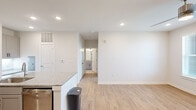 This well-appointed one-bedroom, one-bathroom unit in Huntsville, Alabama offers a thoughtfully designed open-concept layout across a single floor. Light wood-look flooring flows throughout the main living areas, creating a clean, cohesive aesthetic complemented by crisp white walls and recessed lighting.

The kitchen is a standout feature, showcasing granite countertops, gray shaker-style cabinetry with black hardware, stainless steel appliances including a range and microwave, and a peninsula with an undermount sink — ideal for both meal prep and casual dining. A built-in desk nook provides additional functionality just off the kitchen.

The living area is bright and airy, benefiting from natural light through large windows and a glass door that provides direct outdoor access. A ceiling fan adds comfort to the space.

The bedroom is generously sized, finished with plush wall-to-wall carpeting, a ceiling fan, and a window with outdoor views. An adjacent closet offers dedicated storage space.

The bathroom is finished with a granite-topped vanity featuring gray cabinetry and black hardware, a large mirror, tiled tub-shower combination, and wood-look tile flooring. The overall ambiance throughout is modern, clean, and move-in ready.
