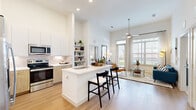 This well-designed single-floor residence offers two bedrooms and two bathrooms within a thoughtfully arranged floor plan. The open-concept living and kitchen area serves as the heart of the home, highlighted by dramatically tall ceilings that amplify the sense of space. Large windows flood the area with natural light, while a ceiling fan enhances comfort in the living room.

The kitchen is both functional and stylish, featuring stainless steel appliances, a combination of white upper cabinetry and warm wood-toned lower cabinets, a tile backsplash, and a peninsula with seating — ideal for casual dining or entertaining. Light wood-tone flooring runs throughout the main living areas, contributing to the home's clean, contemporary aesthetic.

Both bedrooms are carpeted and receive natural light through well-sized windows with views to the outdoors. The primary bedroom includes a walk-in closet with built-in shelving and hanging rods. The bathrooms are finished with marble-style tile surrounds on the tub-shower combinations, complemented by built-in open shelving for convenient storage.

Two dedicated closets provide additional organizational space throughout the unit, rounding out a practical and polished residence.
