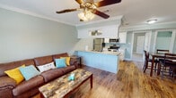 Located at 805 Harmon Dr in Valdosta, Georgia, this two-story home offers a well-designed layout with a cohesive, calming color palette of soft sage green and crisp white throughout. The main floor showcases an open-concept living and kitchen area unified by warm hardwood-style flooring and elegant crown molding. The living room is bright and welcoming, featuring large windows that invite natural light, a ceiling fan, and ample space for comfortable seating. The kitchen is thoughtfully outfitted with white shaker-style cabinetry, granite countertops, stainless steel appliances including a refrigerator, range, and microwave, and a peninsula that connects seamlessly to the living area. A dedicated dining space sits conveniently adjacent to the kitchen and a full bathroom, which features a granite-topped white vanity, tub-shower combo, and hardwood-style flooring. A practical in-unit laundry area houses a full-size washer and dryer with overhead shelving for storage. The upper level includes a carpeted bedroom with a ceiling fan and natural light from a window with blinds. Throughout the home, consistent finishes and a neutral palette create a clean, cohesive, and functional living environment.