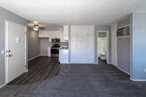 Located at 2700 Iowa Ave in Riverside, California, this single-floor unit offers a well-designed, functional layout with a clean, contemporary aesthetic throughout. The kitchen is a standout feature, outfitted with crisp white shaker-style cabinetry extending to the ceiling for generous storage, light-toned countertops, and a full suite of stainless steel appliances including a gas range, over-the-range microwave, and dishwasher. Wood-look vinyl plank flooring runs through the kitchen and entry areas, providing a warm, durable foundation that transitions seamlessly into plush carpeting in the open living space. The living area is spacious and bright, with neutral gray walls, a ceiling fan, and a large sliding glass door that invites natural light and offers views of the outdoors. A wall-mounted air conditioning unit ensures year-round comfort. The bathroom is finished with matching wood-look flooring, a full tub and shower combination, a vanity with a light countertop, and a window for natural ventilation. A tall, built-in white cabinet unit near the kitchen provides additional storage. The overall design is cohesive and move-in ready, with a neutral color palette and modern finishes throughout.