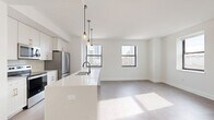 Located at 758 North Broadway in Milwaukee, WI, this well-appointed 3-bedroom, 2-bathroom residence offers a thoughtfully designed single-floor layout. The open-concept kitchen and living area serves as the heart of the home, anchored by a sleek white quartz waterfall island with an undermount sink and matte black faucet. Pendant lighting adds a modern touch above the island, while stainless steel appliances and white shaker cabinetry complete the kitchen. Large black-framed windows flood the living space with natural light and frame views of the Milwaukee skyline. Smooth light-toned flooring runs throughout the main living areas, creating a clean, cohesive aesthetic. The spacious primary bedroom features plush carpeting, multiple windows with city views, and access to a dedicated closet. The bathrooms offer classic charm with hexagonal mosaic tile flooring, white vanity cabinetry, and well-lit mirrors. A central hallway connects the three bedrooms, two bathrooms, and in-unit laundry, ensuring a practical and efficient flow. Three closets provide ample storage throughout. The overall design is bright, modern, and minimal, with crisp white walls and contemporary details that create an inviting, move-in-ready living environment.