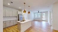 Located at 382 Red Bud Cir in Hendersonville, NC, this well-appointed single-floor home offers 3 bedrooms and 2 bathrooms with a clean, modern aesthetic throughout. The open-concept kitchen and living area serves as the heart of the home, showcasing light hardwood-style flooring, recessed lighting, and a central kitchen island with a white quartz countertop and gold-toned pendant lights overhead. The kitchen is equipped with stainless steel appliances, including a range with microwave above, a refrigerator, and ample white shaker cabinetry accented with brushed gold hardware and a classic white subway tile backsplash. The adjoining living room benefits from a ceiling fan, large windows, and a glass door that opens to an outdoor balcony, filling the space with natural light and outdoor views. The spacious primary bedroom includes recessed lighting, a ceiling fan, and access to a generous walk-in closet with wire shelving and carpeted flooring. Additional bedrooms feature plush carpeting, ceiling fans, and natural light from windows. The two bathrooms are finished in a clean, minimalist style with wood-look flooring, a walk-in shower, and a vanity. This home combines functional design with modern finishes in a comfortable Hendersonville setting.