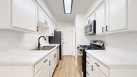 Located at 730 West Algonquin Road in Des Plaines, IL, this two-bedroom, two-bathroom residence offers a thoughtfully designed single-floor layout with a clean, modern aesthetic throughout. The open living room is bathed in natural light from a large sliding glass door that opens to an outdoor view, and is finished with plush carpeting, a ceiling fan, and baseboard heating. Adjacent to the living area, the galley-style kitchen has been stylishly updated with crisp white shaker cabinets, black hardware accents, quartz countertops, white subway tile backsplash, and stainless steel appliances including a gas range and built-in microwave. Light wood-style flooring runs through the kitchen, adding warmth to the bright, clean space. The generously sized primary bedroom features wide windows that invite natural light, soft carpet underfoot, and dual closets with built-in shelving, providing ample storage. The second bedroom is equally well-lit with a multi-pane window and carpeted flooring. Both bathrooms are finished with white subway tile, wood-look flooring, and coordinating black hardware, maintaining a consistent modern design language. A dedicated hallway and closet round out the functional layout of this well-appointed Des Plaines residence.