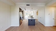 Located at 6600 Main St in Miami Lakes, Florida, this multi-story property spans three floors and is designed with a clean, contemporary aesthetic. Warm neutral tones, recessed lighting, and wood-look flooring flow consistently throughout, creating a cohesive and inviting atmosphere.

The main living level showcases an open-concept kitchen equipped with stainless steel appliances, dark cabinetry, a large center island with a white countertop and built-in sink, and pendant lighting overhead. Track lighting and a ceiling fan complement the bright, airy living area, which benefits from natural light streaming through multiple windows.

The bathrooms are well-appointed, featuring glass-enclosed walk-in showers with floor-to-ceiling tile surround, dark vanity cabinetry, and wood-look flooring for a refined, spa-like feel. The bedrooms are generously sized with large windows that bring in natural light, and select rooms include walk-in closets.

A dedicated in-unit laundry room houses a full-size washer and dryer set with overhead wire shelving for added storage. The staircase, detailed with white balusters and a rich wood handrail, connects all three levels gracefully. The ground floor includes a private garage with ample space, completing this functional and modern property.