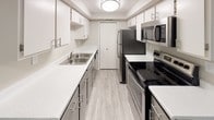 This single-floor unit offers a functional and comfortable layout with a clean, neutral aesthetic throughout. The living area features durable hardwood-style flooring in a warm gray tone, neutral-painted walls, and a textured ceiling, creating a bright and open atmosphere. A large window fitted with vertical blinds allows natural light to fill the space, adding to its airy feel.

The galley-style kitchen is efficiently designed with white cabinetry, white quartz countertops, and a stainless steel sink. It is equipped with a full suite of stainless steel appliances, including a refrigerator, electric range, and over-the-range microwave, making it both stylish and practical.

The bedrooms are generously sized, each featuring plush carpeting, neutral wall tones, textured ceilings, and windows with vertical blinds that provide natural light and outdoor views. These rooms offer a quiet, comfortable retreat within the unit.

The bathroom is well-appointed with a white quartz vanity top, a round undermount sink, brushed nickel fixtures, a large mirror with overhead lighting, and a full tub-shower combination with clean white surround. Light tile flooring completes the bathroom's crisp, functional design. Overall, the unit presents a cohesive and move-in-ready living environment.