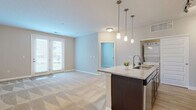 Located at 291 Graceland Blvd in Columbus, OH, this well-appointed one-bedroom, one-bathroom unit offers a thoughtfully designed single-floor layout. The open-concept living area seamlessly connects the kitchen, dining, and living spaces, creating a bright and functional hub for everyday life. The kitchen is a standout feature, boasting rich dark-wood cabinetry, granite countertops, a central island with pendant lighting, a subway tile backsplash, and stainless steel appliances. Wood-style flooring grounds the kitchen and transitions into plush carpeting throughout the living and bedroom areas. The living room is bathed in natural light through French doors that open directly onto a private patio, offering a pleasant outdoor retreat. The bedroom is a comfortable, carpeted retreat with a large window overlooking the outdoors and direct access to two closets, including a spacious walk-in with wire shelving. The bathroom features wood-style flooring, a dark-wood vanity with a stone-top sink, and a large mirror. Completing this unit is a convenient in-unit laundry area with a stacked washer and dryer, adding a practical touch to this well-rounded and modern living space.