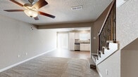 Located at 1755 Emily Lane in Belton, Missouri, this two-story home offers a well-designed layout spread across two floors. The main level features an open-concept living room and kitchen, where plush carpet in the living area transitions to durable wood-look flooring in the kitchen. The kitchen is outfitted with crisp white shaker cabinetry, granite countertops, stainless steel appliances including a dishwasher, electric range, and microwave, plus recessed lighting and a sliding door providing access to the exterior. A ceiling fan with light fixture keeps the living area comfortable, and a textured ceiling adds character throughout the main floor. Three bathrooms serve the home, including one featuring a tub/shower combination with wood-look flooring and another with a granite-topped vanity and undermount sink. Upstairs, two bedrooms offer carpeted floors and ceiling fans, with the primary bedroom showcasing vaulted ceilings and a built-in closet with integrated shelving and a hanging rod. A dedicated walk-in closet with built-in organizers provides ample storage. A staircase with elegant dark iron balusters connects the two levels, completing this functional and attractively finished home.