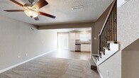 Located at 1755 Emily Lane in Belton, Missouri, this two-story home offers a well-designed layout spread across two floors. The main level features an open-concept living room and kitchen, where plush carpet in the living area transitions to durable wood-look flooring in the kitchen. The kitchen is outfitted with crisp white shaker cabinetry, granite countertops, stainless steel appliances including a dishwasher, electric range, and microwave, plus recessed lighting and a sliding door providing access to the exterior. A ceiling fan with light fixture keeps the living area comfortable, and a textured ceiling adds character throughout the main floor. Three bathrooms serve the home, including one featuring a tub/shower combination with wood-look flooring and another with a granite-topped vanity and undermount sink. Upstairs, two bedrooms offer carpeted floors and ceiling fans, with the primary bedroom showcasing vaulted ceilings and a built-in closet with integrated shelving and a hanging rod. A dedicated walk-in closet with built-in organizers provides ample storage. A staircase with elegant dark iron balusters connects the two levels, completing this functional and attractively finished home.