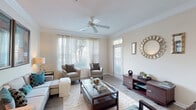 Located at 2305 Global Forum Blvd in Atlanta, GA, this single-floor residence offers a thoughtfully designed layout that balances comfort and functionality throughout. The open-concept living area serves as the heart of the home, featuring crown molding, hardwood-style flooring, a ceiling fan, and large windows dressed with sheer curtains that invite abundant natural light and outdoor views of surrounding greenery. The living space flows seamlessly into a dedicated dining area, which is accented by crown molding, a pendant light fixture, and wall sconces that create an inviting atmosphere for entertaining. The galley-style kitchen is outfitted with warm wood cabinetry, stainless steel appliances including a refrigerator, range, and dishwasher, and a breakfast bar that connects the kitchen to the living spaces. A second open dining or sitting area adjacent to the kitchen provides additional flexibility. The bedroom is generously proportioned, featuring plush carpeting, a ceiling fan, dual windows with sheer panels, and ample space for multiple sleeping arrangements. The full bathroom includes warm wood vanity cabinetry, granite-style countertops, a large mirror, and a shower-tub combination. Completing the home is a dedicated in-unit laundry area with a washer and dryer and overhead storage shelving.