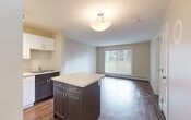 Located at 2000 Saddleback Road NW, this well-designed one-bedroom, one-bathroom unit makes smart use of its compact footprint across a single floor. The open-concept kitchen and living area serves as the heart of the space, showcasing rich dark lower cabinetry contrasted with crisp white upper cabinets and light countertops. A central kitchen island provides additional prep and storage space, while a full suite of appliances — including a refrigerator, electric range, and dishwasher — adds everyday convenience. Hardwood-style flooring runs throughout the kitchen and living area, lending warmth and a cohesive look, and a large sliding glass door fills the living space with natural light while offering a view of the outdoors. The bedroom is a calm and comfortable retreat featuring plush carpeting, a window with blinds, a baseboard heater, and a mirrored sliding-door closet for ample storage. The bathroom is clean and functional, complete with a full tub-shower combination with white tile surround. Adding further practicality, the unit includes an in-suite laundry area with a stacked washer and dryer. A textured ceiling and neutral tones throughout create a consistent, understated aesthetic across the entire unit.