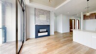 Located at 1645 S 101st E Ave in Tulsa, Oklahoma, this thoughtfully designed 2-bedroom, 3-bathroom home offers a seamless blend of modern aesthetics and functional living. Light oak hardwood flooring flows throughout the space, complementing the clean white walls and warm wood accents visible in the rich teak-tone interior doors.

The kitchen is a standout feature, showcasing a combination of white lower cabinetry and wood-toned upper cabinets, a classic white subway tile backsplash, sleek marble-look quartz countertops, a black undermount sink, and a statement globe pendant light — all coming together to create a contemporary yet inviting culinary space.

The living area is anchored by a striking fireplace finished with stacked stone tile and a bold navy surround, set beneath a tray ceiling that adds architectural depth. Large glass sliding doors open to a balcony, bringing in abundant natural light.

The two bedrooms are bright and airy, with large black-framed windows offering open views. The primary bedroom includes access to a dedicated closet with built-in shelving and marble-look tile flooring. The bathrooms are elegantly appointed with frameless glass shower enclosures, marble-look tile flooring, LED-backlit mirrors, and gold fixtures that add a luxurious finishing touch.