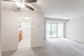 This single-floor residence offers a well-organized layout that balances communal and private spaces effectively. The living area is notably bright, anchored by a large sliding glass door that opens to a balcony overlooking lush, mature trees, allowing generous natural light to fill the space. Neutral-toned carpet and beige walls provide a clean, versatile backdrop throughout the living and bedroom areas.

The kitchen is positioned adjacent to the living area and features warm oak cabinetry, dark laminate countertops, a stainless steel sink, and white appliances including a gas range and dishwasher. A window above the range brings in additional natural light. The tile flooring in the kitchen provides a practical contrast to the carpeted areas throughout the rest of the unit.

The bedrooms are comfortably sized, each featuring soft carpeting and neutral walls. One bedroom includes a built-in closet with bifold doors, while others offer windows framing views of surrounding greenery. Two bathrooms serve the unit, each finished with tile flooring, oak vanities with integrated countertops, wall-mounted mirrors, and overhead lighting. One bathroom includes a full tub-shower combination with white tile surround, while the second functions as a half bath.