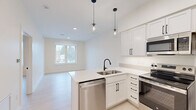 Located at 220 Quimby St NE, Unit 304 in Grand Rapids, Michigan, this thoughtfully designed unit offers a clean, modern aesthetic across its single floor. The open-concept layout connects the kitchen and living area seamlessly, making efficient use of the available space. The kitchen is a standout feature, showcasing white shaker-style cabinetry with matte black hardware, light quartz countertops, and a peninsula with an undermount sink. A full suite of stainless steel appliances — including a refrigerator, electric range, microwave, and dishwasher — completes the space. Stylish globe pendant lights hang above the peninsula, adding a contemporary touch. Light wood-tone flooring flows consistently throughout, enhancing the bright, airy feel created by the crisp white walls. The living area benefits from a window that invites natural light and offers views of the surrounding neighborhood. The bedroom is a calm, understated space with large windows that frame outdoor views and provide ample natural light. The bathroom features a white vanity with matte black fixtures, a walk-in shower, and matching black towel bars and hardware, maintaining the cohesive modern design found throughout the unit. Overall, the space presents a fresh, minimalist character well-suited for comfortable everyday living.