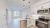Located at 220 Quimby St NE, Unit 304 in Grand Rapids, Michigan, this thoughtfully designed unit offers a clean, modern aesthetic across its single floor. The open-concept layout connects the kitchen and living area seamlessly, making efficient use of the available space. The kitchen is a standout feature, showcasing white shaker-style cabinetry with matte black hardware, light quartz countertops, and a peninsula with an undermount sink. A full suite of stainless steel appliances — including a refrigerator, electric range, microwave, and dishwasher — completes the space. Stylish globe pendant lights hang above the peninsula, adding a contemporary touch. Light wood-tone flooring flows consistently throughout, enhancing the bright, airy feel created by the crisp white walls. The living area benefits from a window that invites natural light and offers views of the surrounding neighborhood. The bedroom is a calm, understated space with large windows that frame outdoor views and provide ample natural light. The bathroom features a white vanity with matte black fixtures, a walk-in shower, and matching black towel bars and hardware, maintaining the cohesive modern design found throughout the unit. Overall, the space presents a fresh, minimalist character well-suited for comfortable everyday living.