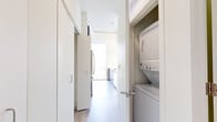 Located in Chicago's vibrant Old Town neighborhood, this modern high-rise unit at 343 W Schiller St offers a sleek, contemporary design with an abundance of natural light. The open living area is defined by dramatic floor-to-ceiling windows that frame sweeping panoramic views of the Chicago skyline and surrounding rooftops, creating a bright and airy atmosphere throughout.

The kitchen is outfitted with modern flat-front cabinetry in a rich dark finish, white quartz countertops, stainless steel appliances including a full-size refrigerator and gas range, and a large undermount sink — all complemented by a tall window that brings in additional natural light and city views.

Light wood-tone flooring runs throughout the unit, lending a clean, cohesive aesthetic. The bedroom features a floor-to-ceiling window with elevated city views and direct access to a walk-in closet with built-in shelving. The bathroom is appointed with a dual-sink vanity featuring dark wood cabinetry, white countertops, large mirrors, and light tile flooring. A dedicated in-unit laundry closet with a stacked washer and dryer adds everyday convenience. The overall ambiance is clean, minimalist, and sophisticated.