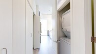 Located in Chicago's vibrant Old Town neighborhood, this modern high-rise unit at 343 W Schiller St offers a sleek, contemporary design with an abundance of natural light. The open living area is defined by dramatic floor-to-ceiling windows that frame sweeping panoramic views of the Chicago skyline and surrounding rooftops, creating a bright and airy atmosphere throughout.

The kitchen is outfitted with modern flat-front cabinetry in a rich dark finish, white quartz countertops, stainless steel appliances including a full-size refrigerator and gas range, and a large undermount sink — all complemented by a tall window that brings in additional natural light and city views.

Light wood-tone flooring runs throughout the unit, lending a clean, cohesive aesthetic. The bedroom features a floor-to-ceiling window with elevated city views and direct access to a walk-in closet with built-in shelving. The bathroom is appointed with a dual-sink vanity featuring dark wood cabinetry, white countertops, large mirrors, and light tile flooring. A dedicated in-unit laundry closet with a stacked washer and dryer adds everyday convenience. The overall ambiance is clean, minimalist, and sophisticated.