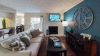 This single-story 1-bedroom, 1-bathroom residence offers a thoughtfully designed layout that maximizes both comfort and functionality. The living room serves as the centerpiece of the unit, featuring a white brick fireplace, hardwood-style flooring, and a bold teal accent wall that adds a striking visual element. A sliding glass door provides access to an outdoor area, allowing natural light to fill the space.

The galley-style kitchen is efficiently arranged with dark granite countertops, white cabinetry, black appliances including a refrigerator, electric range, and dishwasher, and a double stainless steel sink positioned beneath a window. The kitchen flows directly into a dedicated dining area, which is brightened by multiple windows and a pendant light fixture overhead.

The bedroom is generously proportioned, featuring plush carpeting, a ceiling fan, and a bay-style window arrangement that invites abundant natural light. The full bathroom includes a wide vanity with dark granite countertops, white cabinetry, hardwood-style flooring, and a tub-shower combination.

A dedicated laundry area houses a full-size side-by-side washer and dryer, adding everyday convenience. Throughout the unit, textured ceilings and warm, neutral tones contribute to a cohesive and inviting ambiance.