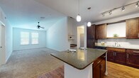 Located at 101 Integra Village Trail in Sanford, Florida, this single-story residence offers a thoughtfully designed open-concept layout that seamlessly connects the kitchen, dining, and living areas. The kitchen is a standout feature, showcasing rich dark-wood cabinetry, granite countertops, a subway tile backsplash, and a full suite of stainless steel appliances including a refrigerator, range, microwave, and dishwasher. A central island with pendant lighting provides additional prep space and casual seating, while wood-look flooring grounds the kitchen and dining areas with warmth and durability. The living area transitions to plush carpeting and is equipped with a ceiling fan, offering a comfortable and inviting atmosphere. Multiple bedrooms feature soft carpeting, ceiling fans, and bright windows that allow natural light to fill each room. The bathrooms are finished with dark wood vanities, white countertops, wood-look flooring, and tiled tub-shower combinations, reflecting a consistent and refined design palette throughout. Built-in shelving accents add functional character to the bathroom spaces. The overall design maintains a clean, neutral aesthetic with modern finishes, creating a cohesive and move-in-ready living environment.