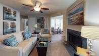 Located at 1916 Sam Rittenberg Blvd in Charleston, SC, this single-floor residence offers a thoughtfully designed layout with comfortable living spaces and cohesive finishes throughout. The kitchen is well-equipped with dark espresso cabinetry, granite-style countertops, black appliances including a refrigerator, dishwasher, and range, and a peninsula with bar seating — ideal for casual dining. Wood-style flooring runs through the kitchen and transitions seamlessly into the adjacent dining area, which features a pendant-lit ceiling and space for a round dining table. The living room is a central gathering space highlighted by a fireplace, ceiling fan, and neutral carpet. It opens into a bright sunroom or sitting area filled with natural light from large windows, providing a versatile secondary lounge space. The bedrooms are carpeted and generously sized, each featuring ceiling fans, windows with natural light, and ample room for full furniture arrangements. The bathroom includes a dark-vanity with granite-style countertop, a tub-shower combination, and wood-style flooring. Throughout the residence, a soft blue and beige color palette creates a calm, cohesive ambiance, making this a comfortable and functional home in the heart of Charleston.
