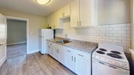 Located at 1107 W Rowan St in Fayetteville, NC, this single-floor home offers a clean, functional layout with thoughtful updates throughout. The kitchen is a standout feature, showcasing white shaker-style cabinetry with gold hardware, granite countertops, a subway tile backsplash, and durable wood-look flooring. White appliances, including a refrigerator and range, complement the bright, cohesive aesthetic. The bedrooms are carpeted and bathed in natural light courtesy of multiple windows fitted with blinds. Ceiling fans provide year-round comfort, and neutral beige walls create a calm, versatile backdrop throughout. The bathroom features a classic black-and-white tile design, with crisp white subway tile surrounding a full bathtub and shower combo, accented by bold black border tile and a mosaic tile floor — a timeless look that adds character to the space. The dollhouse view reveals a straightforward, open floor plan that connects the living and kitchen areas seamlessly, with bedrooms and the bathroom branching off from a central corridor. Overall, this home presents a well-maintained, move-in-ready space with a blend of classic detailing and modern updates.