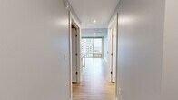 Located in the heart of downtown Grand Rapids, this two-bedroom, two-bathroom residence at 15 Ottawa Ave NW offers a sleek urban living experience with modern design throughout. Light wood-tone flooring runs continuously across the single-floor layout, complemented by soft gray walls and exposed concrete ceilings that lend an industrial-chic character to the space.

The kitchen is well-appointed with white cabinetry, a textured tile backsplash, dark countertops, and a full suite of stainless steel appliances including a range, microwave, dishwasher, and refrigerator. Recessed lighting and a mirrored backsplash panel enhance the sense of brightness and depth.

A central hallway connects the main living areas, leading to two generously sized bedrooms. The primary bedroom is a spacious retreat featuring floor-to-ceiling windows that frame sweeping views of the Grand Rapids skyline, while the second bedroom also benefits from large windows and includes a dedicated closet with built-in shelving. Both bedrooms showcase exposed concrete ceilings, adding to the loft-inspired aesthetic.

The two bathrooms are identically finished with gray tile surrounds, white floating vanities, large mirrors, and wood-look flooring — one featuring a walk-in shower and the other a soaking tub-shower combination. The overall ambiance is clean, contemporary, and urban.