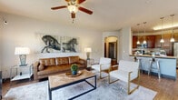 This single-story, 2-bedroom, 2-bathroom home delivers a thoughtfully designed layout with a comfortable blend of style and practicality. The open living and dining area serves as the heart of the home, featuring wood-look flooring, a ceiling fan, and an elegant arched passage that connects to the rest of the space. The living room is bright and inviting, offering ample room for seating and everyday living. Adjacent to it, the dining area is bathed in natural light through a wraparound set of large windows with blinds, creating an airy, welcoming atmosphere for meals. The kitchen is well-equipped with rich dark wood cabinetry, granite countertops, stainless steel appliances including a refrigerator, range, and microwave, and a central island with bar seating and pendant lighting overhead. Wood-look flooring carries throughout the main living areas, adding warmth and cohesion. The primary bedroom is generously sized with plush carpeting, and both bedrooms are served by dedicated closets, including a spacious walk-in closet with multi-tier wire shelving. The bathrooms feature tub-shower combinations with neutral tile finishes. A dedicated laundry room with a full-size washer and dryer adds everyday convenience, completing this well-rounded home.