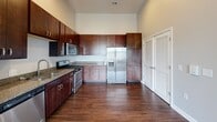 Located at 1700 Lake Superior Rd in Valparaiso, Indiana, this two-bedroom, two-bathroom unit offers a well-designed single-floor layout with a thoughtful mix of finishes throughout. The kitchen is a standout feature, boasting rich dark wood cabinetry that extends to the ceiling for generous storage, granite countertops, and a full suite of stainless steel appliances including a gas range, microwave, dishwasher, and French door refrigerator, all set atop durable hardwood-style flooring. Both bedrooms are carpeted and filled with natural light from large windows that offer views of the surrounding neighborhood. The primary bedroom includes a spacious walk-in closet with wire shelving, while the second bedroom features a built-in double closet. Vaulted ceiling accents add architectural interest to the sleeping areas. The primary bathroom offers a double vanity with granite countertops and hardwood-style flooring, while the second bathroom features a tub-shower combo with tile surround and a single vanity. A dedicated closet provides additional storage. Neutral tones and clean finishes throughout the unit create a cohesive, move-in-ready atmosphere.