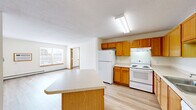 Located at 680 12th St SW in Forest Lake, Minnesota, this two-bedroom, one-bathroom unit offers a functional and well-organized single-floor layout. The open kitchen and living area serves as the heart of the home, featuring warm oak cabinetry, light-toned countertops, a full suite of white appliances including a refrigerator, electric range, and dishwasher, and a peninsula island that provides additional workspace and casual seating. Light hardwood-style flooring runs throughout the kitchen and living areas, complemented by a ceiling fan overhead. A large window with horizontal blinds floods the living space with natural light and offers exterior views. The two bedrooms are carpeted and well-sized, each with baseboard heating and built-in closets with sliding or hinged oak doors. The primary bedroom is a comfortable size, offering ample room for furnishings. The bathroom features warm oak vanity cabinetry, a wide countertop with an undermount sink, a lighted mirror, and a wall-mounted storage cabinet. Additional highlights include a dedicated laundry room and hallway closet storage. Throughout the unit, warm wood trim and neutral walls create a cohesive, inviting atmosphere.