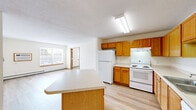 Located at 680 12th St SW in Forest Lake, Minnesota, this two-bedroom, one-bathroom unit offers a functional and well-organized single-floor layout. The open kitchen and living area serves as the heart of the home, featuring warm oak cabinetry, light-toned countertops, a full suite of white appliances including a refrigerator, electric range, and dishwasher, and a peninsula island that provides additional workspace and casual seating. Light hardwood-style flooring runs throughout the kitchen and living areas, complemented by a ceiling fan overhead. A large window with horizontal blinds floods the living space with natural light and offers exterior views. The two bedrooms are carpeted and well-sized, each with baseboard heating and built-in closets with sliding or hinged oak doors. The primary bedroom is a comfortable size, offering ample room for furnishings. The bathroom features warm oak vanity cabinetry, a wide countertop with an undermount sink, a lighted mirror, and a wall-mounted storage cabinet. Additional highlights include a dedicated laundry room and hallway closet storage. Throughout the unit, warm wood trim and neutral walls create a cohesive, inviting atmosphere.