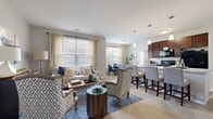 Located at 1155 Winston Decker Dr in Columbus, Ohio, this single-floor 2-bedroom, 2-bathroom residence offers a thoughtfully designed open-concept layout. The combined living, dining, and kitchen area serves as the heart of the home, bathed in natural light from large windows dressed with stylish curtains. The living room features plush carpeting and a welcoming, spacious feel that flows seamlessly into the dining area and kitchen.

The kitchen is a functional standout, showcasing rich dark-wood cabinetry, marble-style countertops, a classic subway tile backsplash, and a full suite of black appliances including a range, microwave, and refrigerator. A breakfast bar with pendant lighting connects the kitchen to the living and dining spaces.

Both bedrooms are carpeted and well-proportioned, with the primary bedroom offering ample space and access to a private en-suite bathroom. The en-suite features dark wood vanity cabinetry, white countertops, wood-look flooring, and a glass-enclosed shower. The second bathroom mirrors this aesthetic and includes a shower-tub combo. Four closets throughout provide generous storage.

A dedicated in-unit laundry room houses a full-size washer and dryer. The residence also includes a private balcony, adding valuable outdoor space. Neutral gray walls and consistent finishes create a cohesive, modern ambiance throughout.