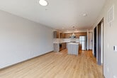 Located at 615 Peterson Road in Burlington, Washington, this thoughtfully designed one-bedroom, one-bathroom unit offers a clean, contemporary aesthetic throughout its single-floor layout. Light wood-tone flooring runs continuously across the entire space, creating a cohesive and warm feel from room to room.

The open-concept kitchen and living area serves as the heart of the unit. The kitchen is equipped with a full suite of stainless steel appliances, including a refrigerator, gas range, microwave, and dishwasher. Flat-front cabinetry in a warm wood-grain finish lines the walls, complemented by light quartz countertops. A central kitchen island provides additional prep space and casual seating potential. A pendant light fixture overhead adds a modern, finishing touch. Notably, a stacked washer and dryer unit is conveniently situated just off the kitchen area, adding practical in-unit laundry access.

The bedroom is a comfortable, well-proportioned space featuring large windows that invite natural light and offer views of the surrounding neighborhood and greenery. Neutral white walls and the consistent wood flooring keep the room bright and versatile.

The bathroom features a soaking tub, toilet, and a vanity with wood-toned cabinetry, maintaining the modern design language found throughout the unit. A dedicated closet provides added storage. The overall ambiance is clean, modern, and move-in ready.