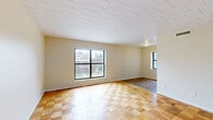 Located at 925 California Ave in Pittsburgh, PA, this two-bedroom, one-bathroom unit offers a practical and functional layout across a single floor. The main living area is generously sized, showcasing distinctive parquet hardwood flooring in a checkerboard pattern that adds character to the space. Natural light filters in through a large picture window, offering views of the surrounding neighborhood.

The spacious primary bedroom features soft carpeting, a built-in louvered closet, and a sliding door connecting to adjacent spaces, providing convenience and flexibility. The second bedroom is also carpeted and includes a window with blinds, offering a quiet and comfortable retreat.

The kitchen is efficiently laid out with warm wood cabinetry, a double-basin stainless steel sink, laminate countertops, and a full-size refrigerator. Stone-look tile flooring ties the kitchen and bathroom together cohesively. The full bathroom includes a tub and shower combination with classic white tile surround, a vanity with storage, and a window for natural ventilation.

Throughout the unit, neutral wall tones and tile ceilings create a clean, understated aesthetic. HVAC vents are present in multiple rooms, ensuring year-round climate comfort. This unit offers a straightforward, livable space well-suited for those seeking a functional home in Pittsburgh's Bellevue neighborhood.