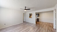 Located at 7114 Texas Rd in Fort Smith, Arkansas, this single-floor, 4-bedroom, 2-bathroom home offers a practical and well-organized layout. The living room serves as the central gathering space, featuring light wood-look laminate flooring, a ceiling fan with integrated lighting, and a textured ceiling. A pass-through opening connects the living area to the kitchen, enhancing the sense of openness between the two spaces. The galley-style kitchen is equipped with dark cabinetry contrasted against light granite-style countertops, white appliances including a refrigerator, electric range, and built-in microwave, along with ample upper and lower cabinet storage. The four bedrooms carry consistent wood-look flooring and neutral wall tones, creating a clean, versatile canvas. The primary bedroom includes a connected bathroom and generous closet space, while at least one additional bedroom features a walk-in style closet with built-in shelving and natural light from a window with blinds. The two bathrooms are finished with dark vanity cabinetry, granite-style countertops, and light flooring. One bathroom includes a tub-shower combination. A hallway and dedicated closet round out the home's efficiently designed floor plan.