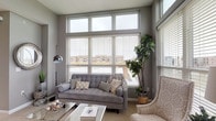 Located at 4272 McCune Ave in Dublin, Ohio, this single-floor residence offers a thoughtfully designed layout that balances modern finishes with comfortable living. The living area is a standout feature, defined by floor-to-ceiling windows on two walls that flood the space with natural light and frame views of the surrounding neighborhood. Elevated clerestory windows add even greater height and openness to the room, which is finished with neutral carpet and soft gray walls throughout.

The kitchen is well-equipped and features rich, dark cabinetry paired with granite countertops and a classic white subway tile backsplash. Wood-look flooring and a peninsula with bar seating create a practical yet stylish space. Pendant lighting and black appliances complete the contemporary aesthetic. A separate galley-style kitchen configuration is also visible, offering dedicated counter space on both sides for efficient meal preparation.

The bedroom is generously sized with plush carpet, soft gray walls, and a window providing natural light. The en-suite bathroom features a dual-sink vanity with dark cabinetry, white countertops, a large framed mirror, and a glass-enclosed shower with wood-look tile flooring, delivering a clean, modern finish throughout.