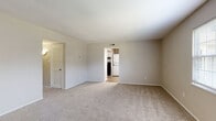 Located at 4594 Wicklow Pl in Virginia Beach, Virginia, this single-floor residence offers a well-organized layout designed for comfortable everyday living. The living area is generously proportioned, finished with neutral-toned carpet and soft beige walls that create a clean, versatile backdrop. A large window allows natural light to fill the space, and a front entry door provides direct access. A louvered closet door adds a functional storage element to the main living area.

The kitchen is a standout feature, outfitted with white shaker-style cabinetry, light stone countertops, and wood-look flooring that lends a modern touch. Black appliances — including a refrigerator, dishwasher, and range — provide a crisp contrast to the white cabinetry. A stacked washer and dryer unit is conveniently located just off the kitchen, adding in-unit laundry capability.

The bedrooms are carpeted and finished in the same neutral palette, each offering a calm and functional environment. Several rooms include closet access and ceiling vents, reflecting thoughtful layout planning. Windows in the bedrooms frame views of surrounding greenery, contributing to a peaceful atmosphere throughout. The overall design is practical, cohesive, and move-in ready.