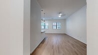This single-floor residence offers a clean, contemporary design characterized by light-toned hardwood-style flooring, crisp white walls, and crown molding throughout the main living areas. The open-concept living and dining space is anchored by a ceiling fan with integrated lighting and receives ample natural light through multiple windows fitted with horizontal blinds. Pendant lighting fixtures hang above the kitchen bar, adding a stylish focal point to the shared living area.

The kitchen is designed for functionality and aesthetics, featuring white shaker-style cabinetry extending to the ceiling, granite countertops, a subway tile backsplash, and a full suite of stainless steel appliances including a refrigerator, range, microwave, and dishwasher. A peninsula counter with bar seating connects the kitchen to the living space, creating a natural flow for everyday living and entertaining.

Multiple bedrooms are present, each featuring hardwood-style flooring and windows that bring in natural views of surrounding greenery. The primary bathroom is notably well-appointed, with a dual-sink vanity, granite countertops, white cabinetry with brushed nickel hardware, and framed mirrors above each sink. The overall ambiance of the space is bright, neutral, and move-in ready, with a consistent modern aesthetic maintained throughout.