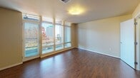 Located on the fourth floor at 1142 Fawcett Ave in downtown Tacoma, Washington, Unit 405 is a thoughtfully designed residence that combines modern finishes with an open, airy layout. Rich hardwood flooring flows throughout the entire unit, lending warmth and continuity from room to room.

The expansive living area is a true standout, featuring dramatic floor-to-ceiling windows that flood the space with natural light and frame lush treetop and city views. A sleek, built-in gas fireplace anchors the room, while a tray ceiling with pendant lighting defines the adjacent dining area, adding architectural character.

The well-appointed kitchen features warm honey-toned cabinetry, dark granite-style countertops, a double stainless steel sink, and a full suite of stainless steel appliances including a gas range, microwave, dishwasher, and a French door refrigerator with an ice maker.

The bedrooms are generously sized, with one offering large windows overlooking the surrounding neighborhood and another featuring a walk-in closet. A full bathroom includes tile flooring, a shower-tub combination, a wide vanity with ample counter space, and a large mirror.

A long, wall-sconce-lit corridor connects the private areas of the unit, and the overall layout provides both comfort and functionality in the heart of Tacoma.