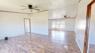 Located at 51000 County Road 512 in Sidon, Mississippi, this single-story home offers four bedrooms, one bathroom, and a combined kitchen and living area across a generously sized floor plan. Wood-look laminate flooring runs throughout the entire home, providing a consistent and cohesive look from room to room.

The combined kitchen and living area anchors the home, with the kitchen featuring white upper and lower cabinetry, a double-basin sink, a range with overhead ventilation, and a refrigerator. Natural light filters in through a window with blinds, brightening the open adjoining living space.

The primary bedroom is notably spacious, equipped with a ceiling fan and light fixture, and benefits from two windows that draw in outdoor views of the surrounding greenery. The remaining three bedrooms are well-sized, each with windows that frame views of the lush yard outside, and several include ceiling fans for added comfort. Two closet doors are visible in one of the bedrooms, offering practical storage.

A hallway connects the bedroom wing to the rest of the home. The bathroom includes a tub-shower combination and toilet. Crown molding details are present in several rooms, adding a subtle decorative touch. The layout is straightforward and functional, making efficient use of the available space throughout.