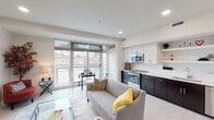 This contemporary single-floor residence offers a thoughtfully designed open-concept layout that seamlessly integrates the living, dining, and kitchen areas. Large floor-to-ceiling windows flood the space with abundant natural light while framing striking urban skyline views, creating a bright and airy atmosphere throughout.

The kitchen is a standout feature, boasting a bold two-tone design with dark lower cabinetry contrasted by crisp white upper cabinets and open floating shelves. It is equipped with stainless steel appliances, including a built-in microwave, electric range, and dishwasher, alongside a sleek white quartz countertop with a deep undermount sink and a white subway tile backsplash.

The open living and dining area benefits directly from the expansive windows, providing an inviting setting with light wood-style flooring that extends throughout the main space. A dedicated dining nook adjacent to the windows offers a comfortable spot to enjoy the urban views.

The bathroom is finished to a high standard, featuring dark tile flooring, a wall-mounted floating vanity with dark wood cabinetry, a white countertop basin, a frameless glass-enclosed shower, and warm vanity lighting. Clean lines and neutral tones give the bathroom a polished, spa-like feel.

Overall, the residence presents a modern urban aesthetic with high-quality finishes, efficient use of space, and a cohesive design language throughout.