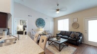 This single-floor residence offers a thoughtfully designed layout that balances comfort and functionality across its living spaces. The open-concept living room serves as the heart of the unit, featuring warm hardwood-style flooring, a ceiling fan with light fixture, and a glass-paneled entry door that invites natural light. A built-in desk nook off the living area provides a dedicated workspace, complemented by upper cabinetry for additional storage.

The kitchen is equipped with rich dark-wood cabinetry extending to the ceiling, granite-style countertops, and black appliances including a refrigerator, range, and over-the-range microwave. An adjacent dining area with hardwood-style flooring provides a practical space for everyday meals.

Each bedroom is carpeted for comfort and includes windows with blinds for light control. One bedroom features direct access to a private bathroom, while an additional full bathroom serves the remaining rooms. Both bathrooms are finished consistently with dark wood vanities, granite-style countertops, hardwood-style flooring, and shower-tub combinations with curtains.

A hallway with a large double-door closet connects the rooms, offering generous storage. Neutral wall tones and consistent finishes throughout create a cohesive, welcoming ambiance.