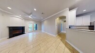 This single-story home offers a thoughtfully designed open-concept floor plan that seamlessly connects the main living and kitchen areas. The living room is bright and welcoming, featuring crown molding, a ceiling fan, a fireplace, and large windows and French doors that fill the space with natural light and provide views of the surrounding greenery. Light-toned ceramic tile flooring runs throughout the main living and kitchen areas, complementing the neutral color palette.

The kitchen is well-equipped with white cabinetry, granite countertops, and stainless steel appliances including a refrigerator with ice maker, electric range, dishwasher, and built-in microwave. An arched passageway and a peninsula with additional counter space enhance the kitchen's functionality and open flow into the living area.

The bedrooms are finished with plush carpeting and feature generous closet space with full double-door closets and built-in hanging rods. A dedicated laundry area accommodates a full-sized washer and dryer. The bathroom includes a curved glass-enclosed shower, a dark wood vanity with a marble-style countertop, and tile flooring. Throughout the home, crown molding, recessed lighting, and arched doorways add refined architectural character.