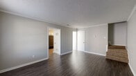 Located in Little Rock, Arkansas, this two-story home offers a clean, functional layout with consistent finishes throughout. The main level features dark hardwood-style flooring that runs through the living areas, complemented by neutral gray walls, white trim, and crown molding. The living room is bright and open, with natural light filtering through a window and a textured ceiling overhead. The kitchen is equipped with white cabinetry, a double sink, black appliances including a gas range and dishwasher, and matching hardwood-style flooring. A half bathroom on the main level features wood-look vinyl flooring and a vanity with ample cabinet storage. The staircase leads to the upper level, where the bedrooms are finished with plush carpet, ceiling fans with lighting, and windows that bring in natural light. The primary bedroom includes an en-suite bathroom featuring a single-sink vanity with generous counter space and cabinetry, a tub-shower combination with tile surround, and wood-look flooring. Additional bedrooms are well-sized with neutral carpet and ceiling fans. The home's consistent use of gray tones, white accents, and durable flooring materials creates a cohesive and move-in-ready atmosphere throughout.